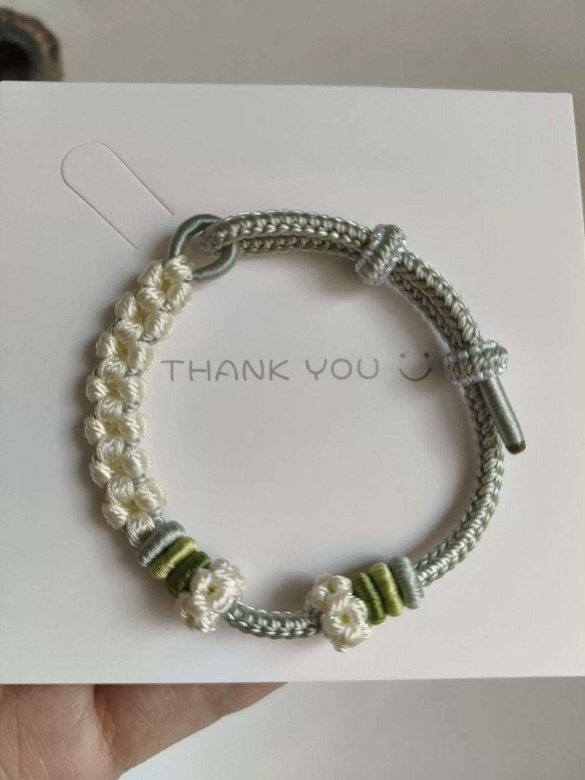 Pulsera de cordón trenzada a mano con flores verdes y blancas