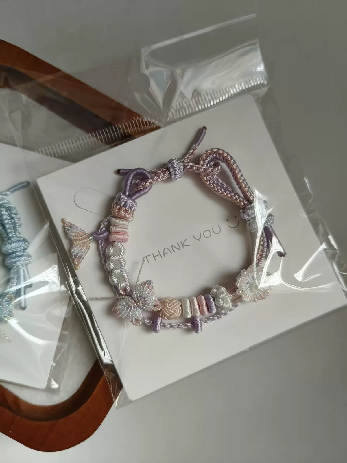 Pulseira tecida à mão com gradiente rosa e branco e charms de borboleta