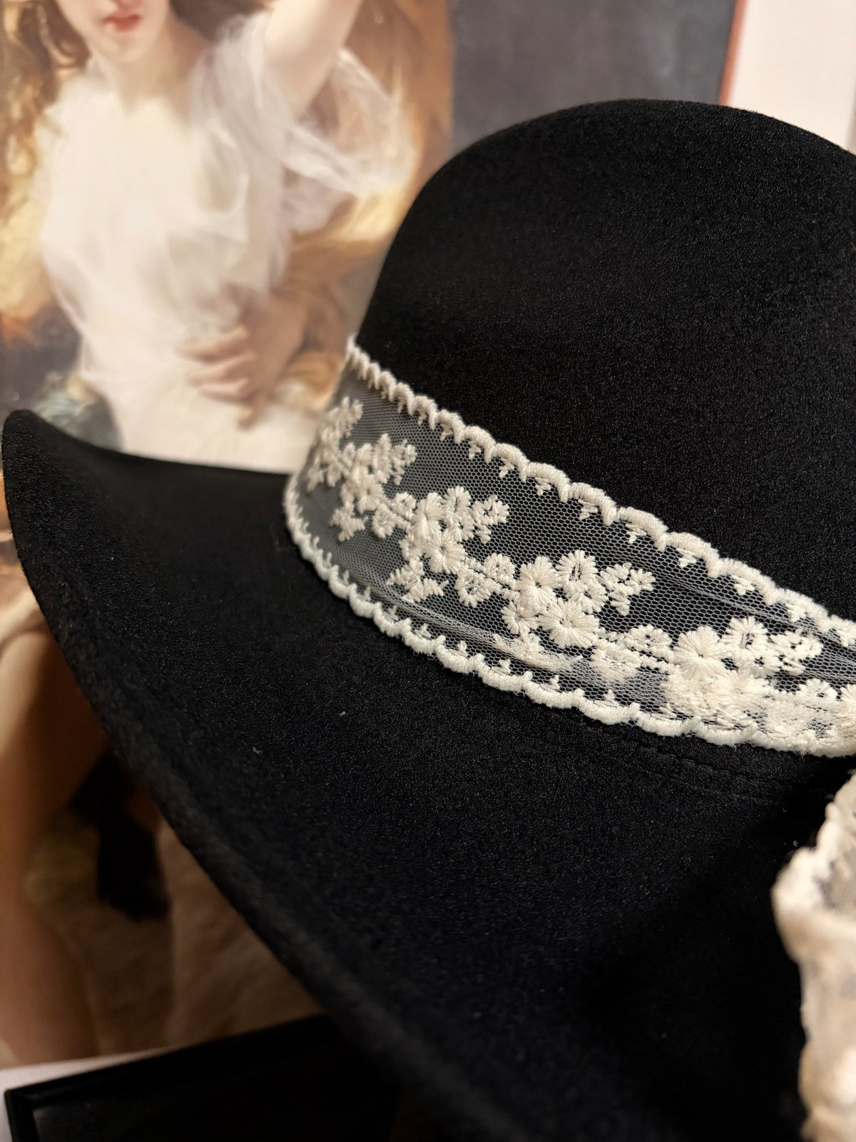 Cappello nero a tesa larga con fiocco in pizzo bianco
