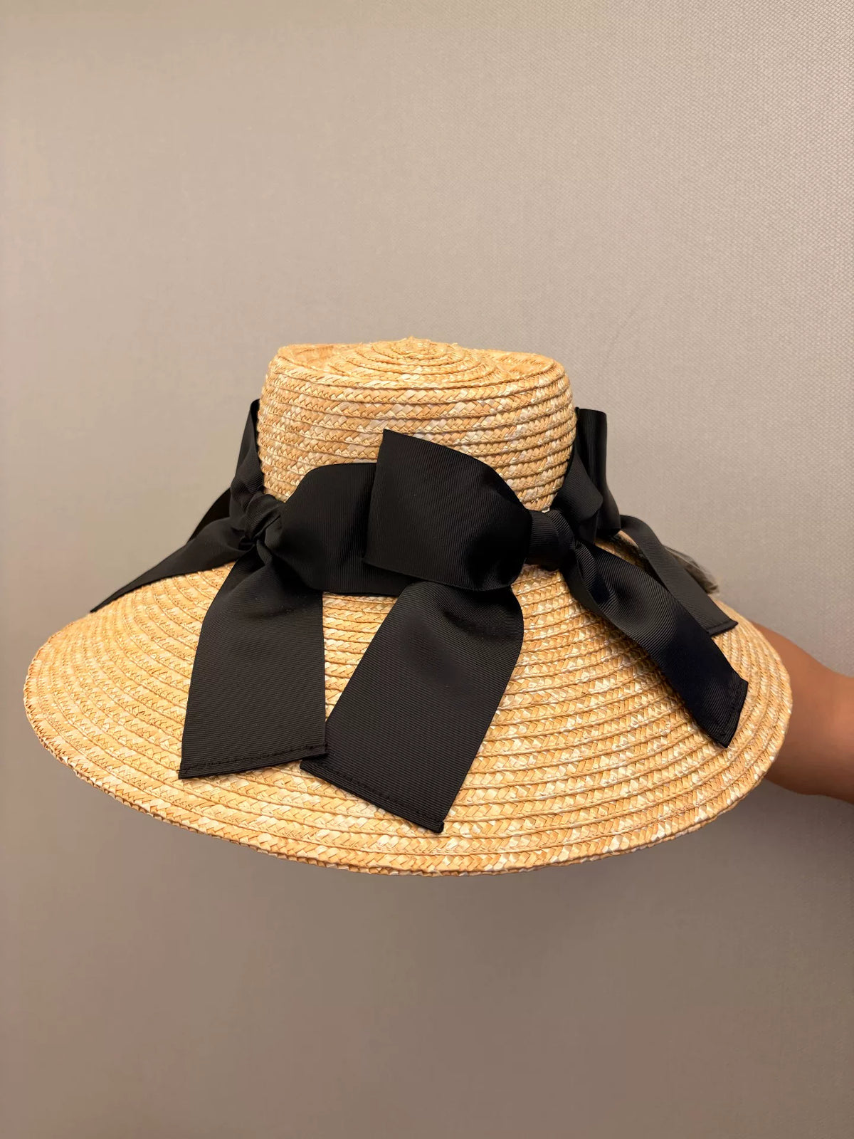 Chapeau de soleil à large bord en paille tissée avec nœud noir