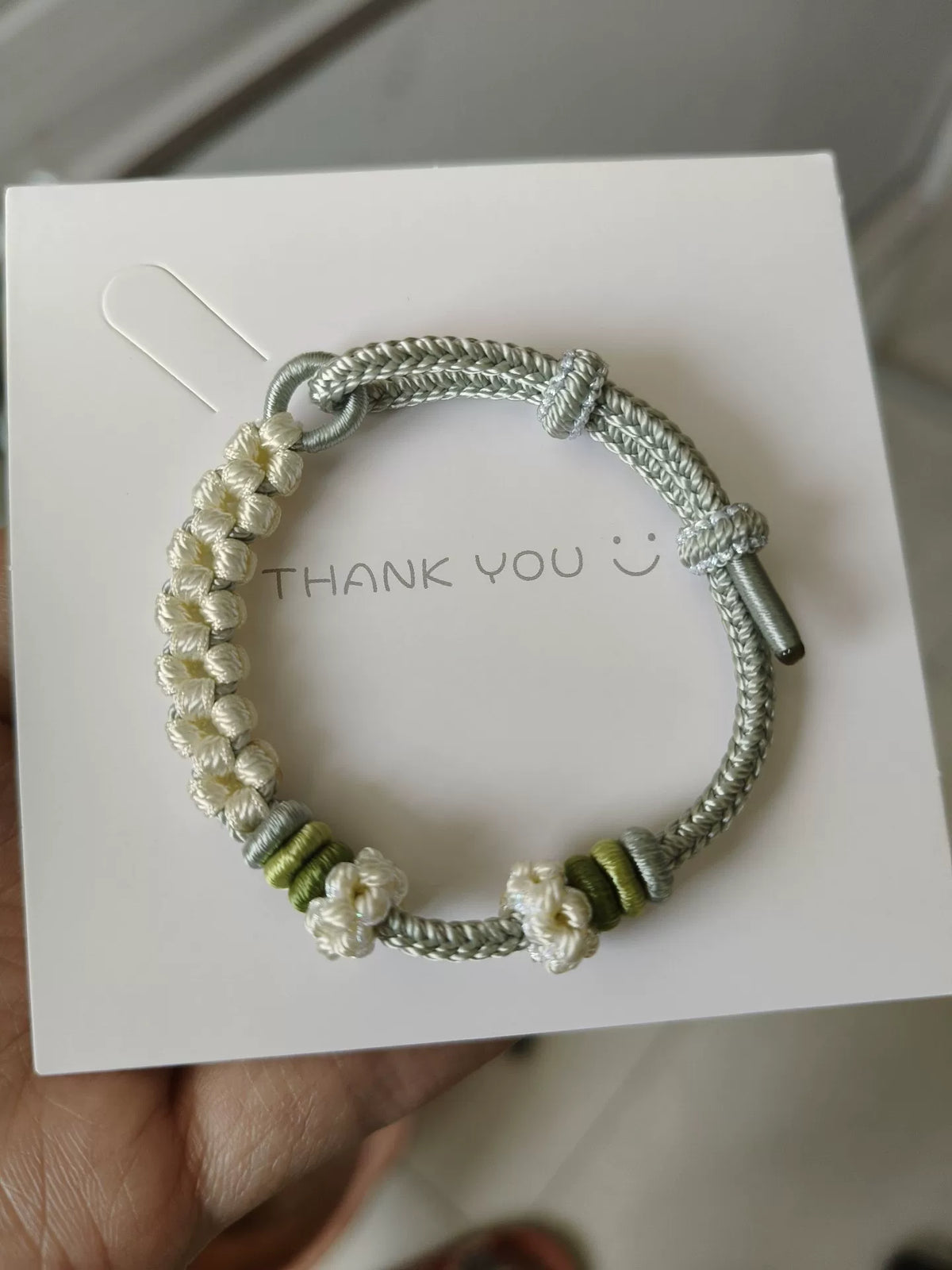 Pulsera de cordón trenzada a mano con flores verdes y blancas