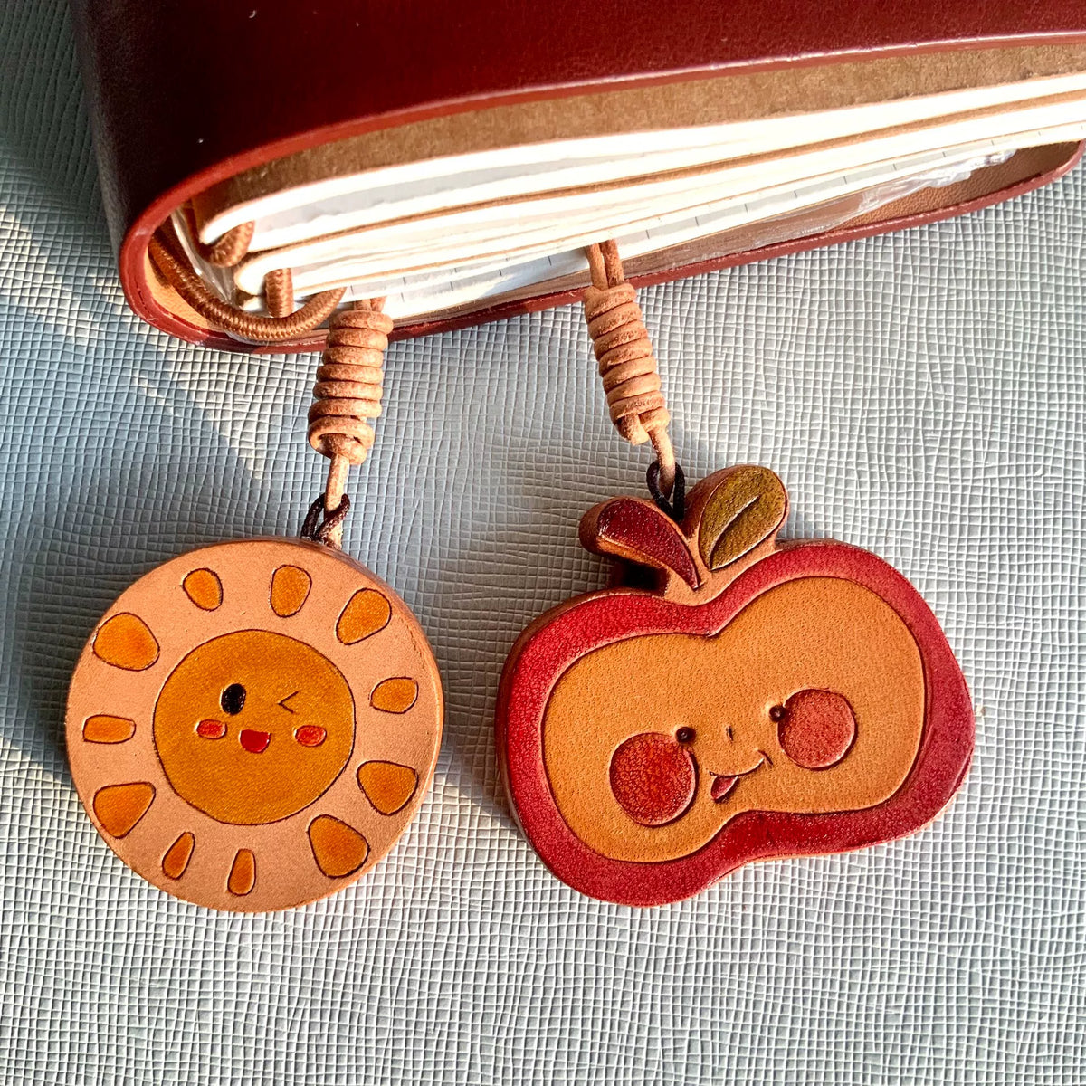 Handgesneden leren charms met zon en appel
