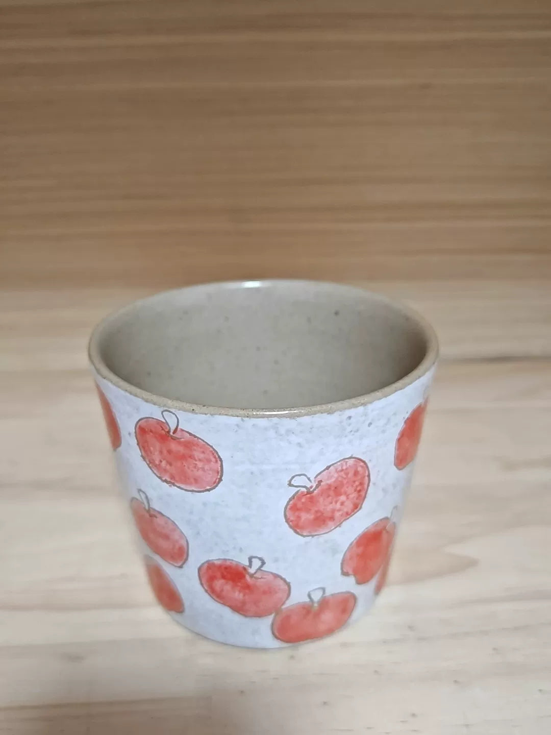 Handgjord keramisk kaffemugg med röda äpplen
