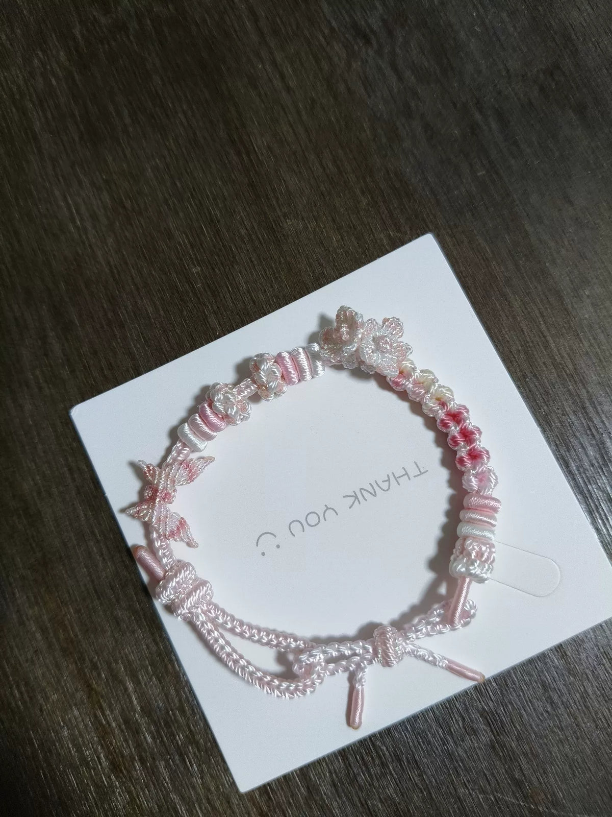Pulsera tejida a mano en degradado rosa y blanco con detalles florales