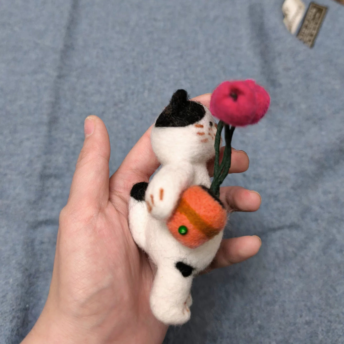 Handgemaakte vilten kattenfiguur van wol met tulpen