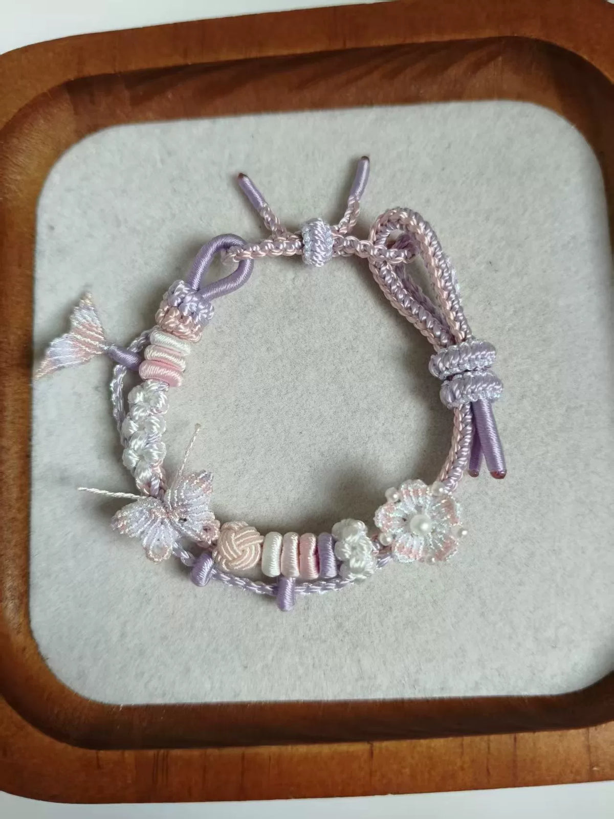 Pulseira tecida à mão com gradiente rosa e branco e charms de borboleta