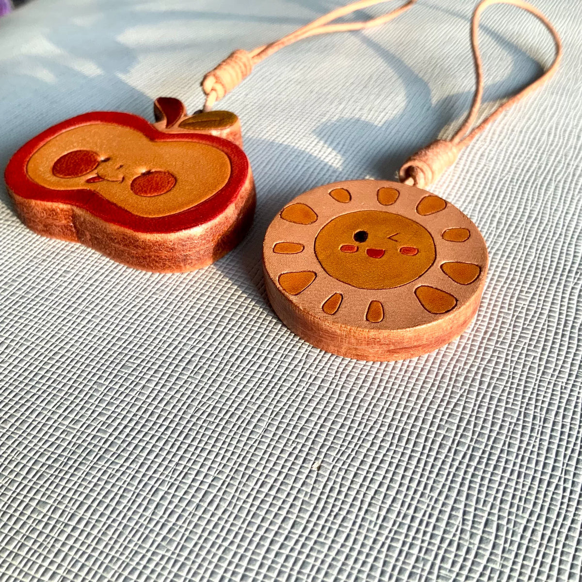 Handgesneden leren charms met zon en appel