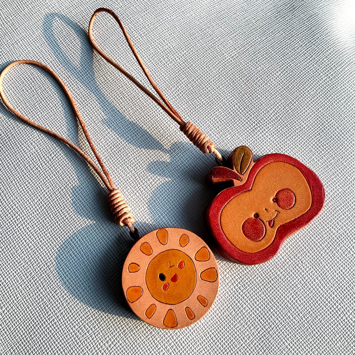 Handgesneden leren charms met zon en appel