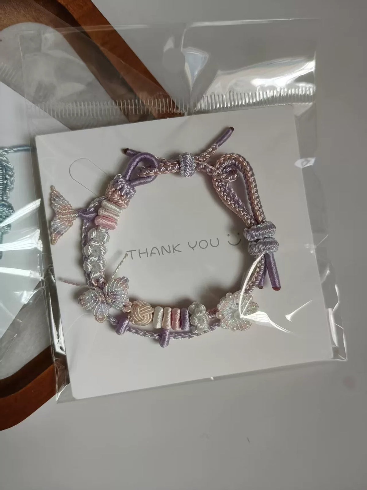 Pulseira tecida à mão com gradiente rosa e branco e charms de borboleta