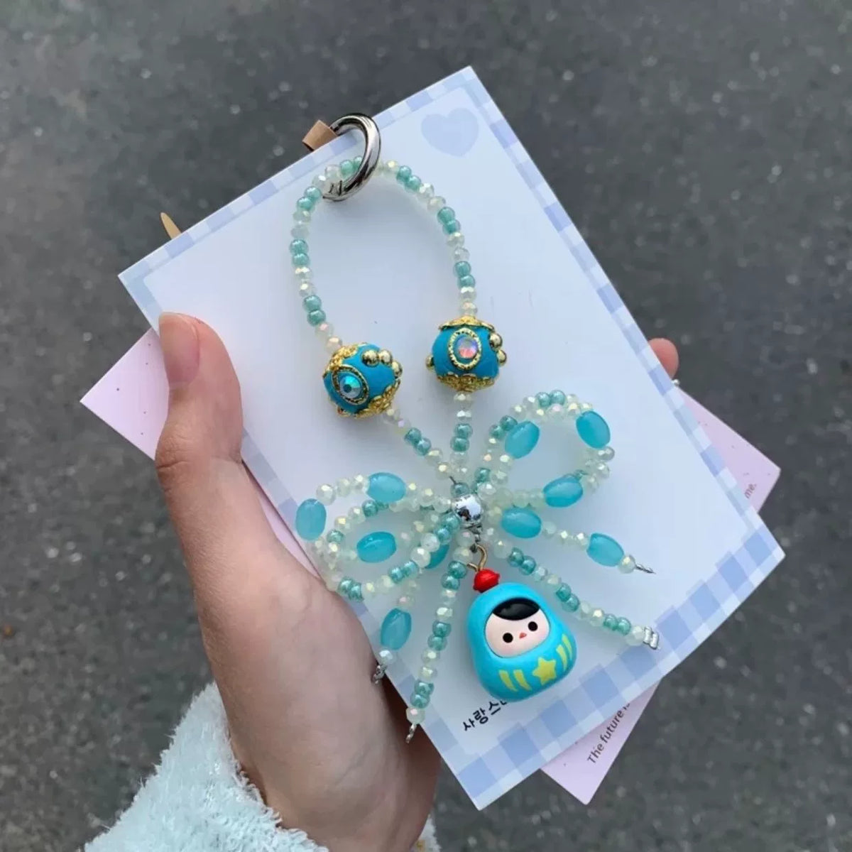 Hellblaue Daruma Handykette mit Perlen