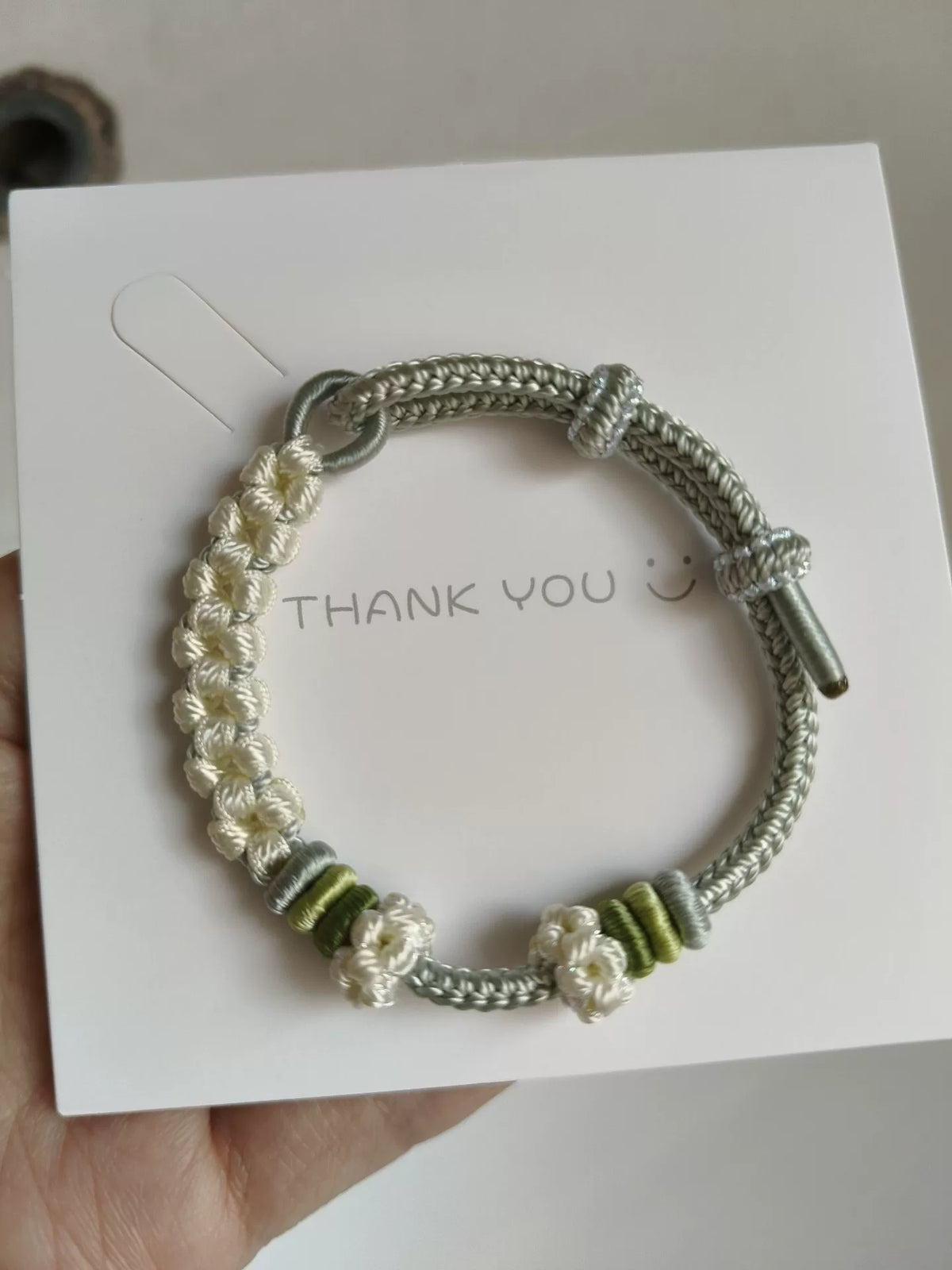 Pulsera de cordón trenzada a mano con flores verdes y blancas