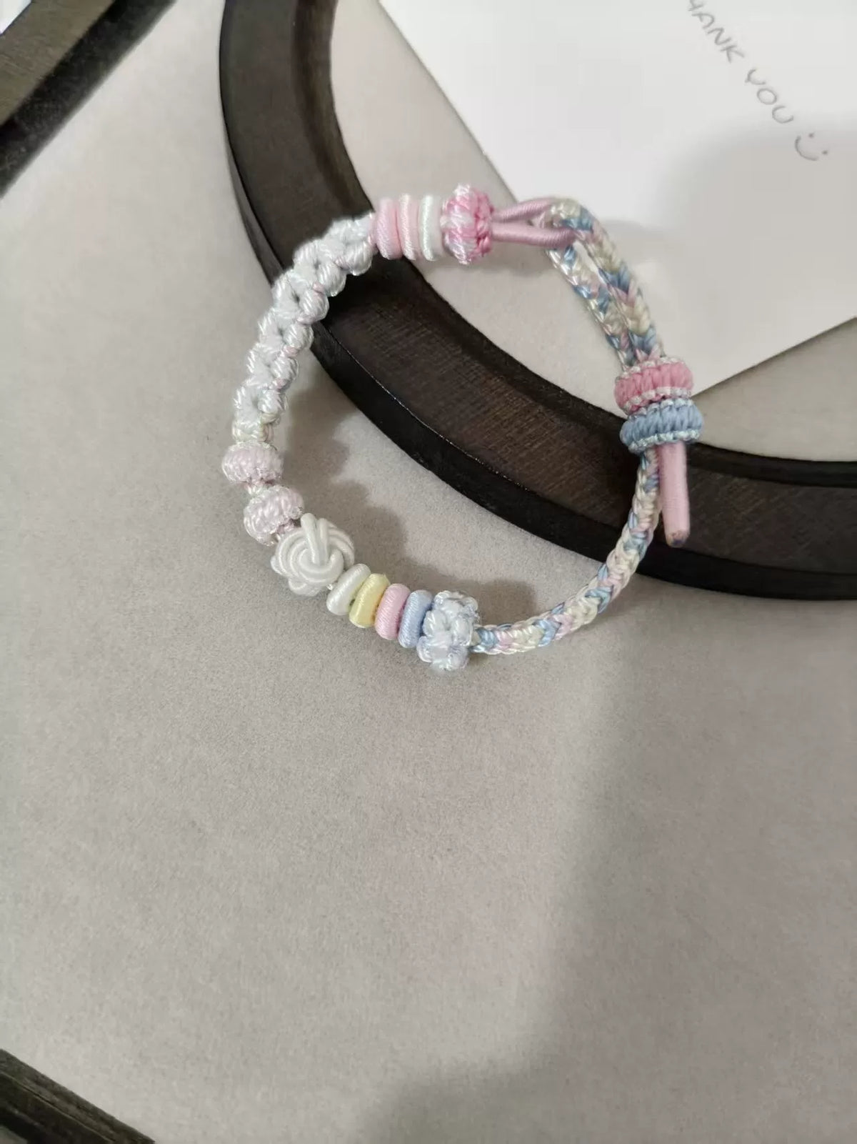 Pulseira de Cordão Tecida à Mão com Gradiente Pastel e Nós em Flor