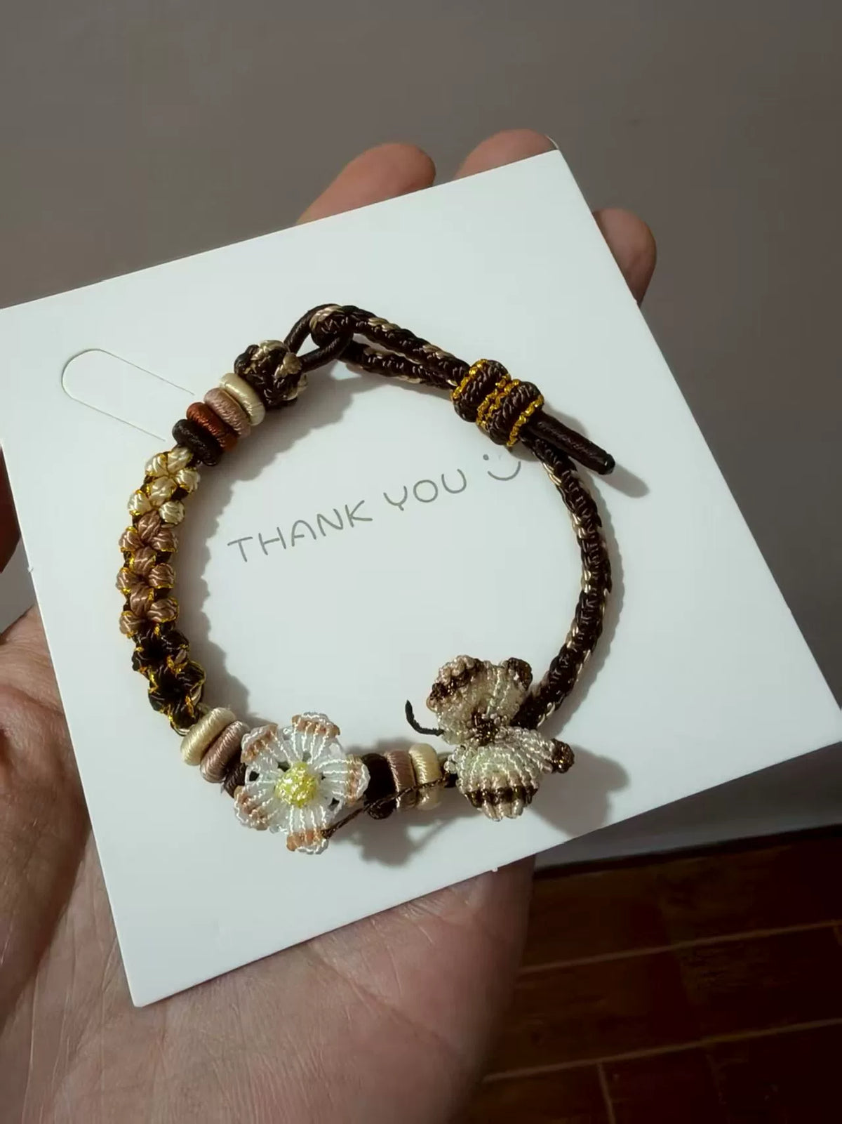 Handgjort flätat armband i brun snodd med blomberlock