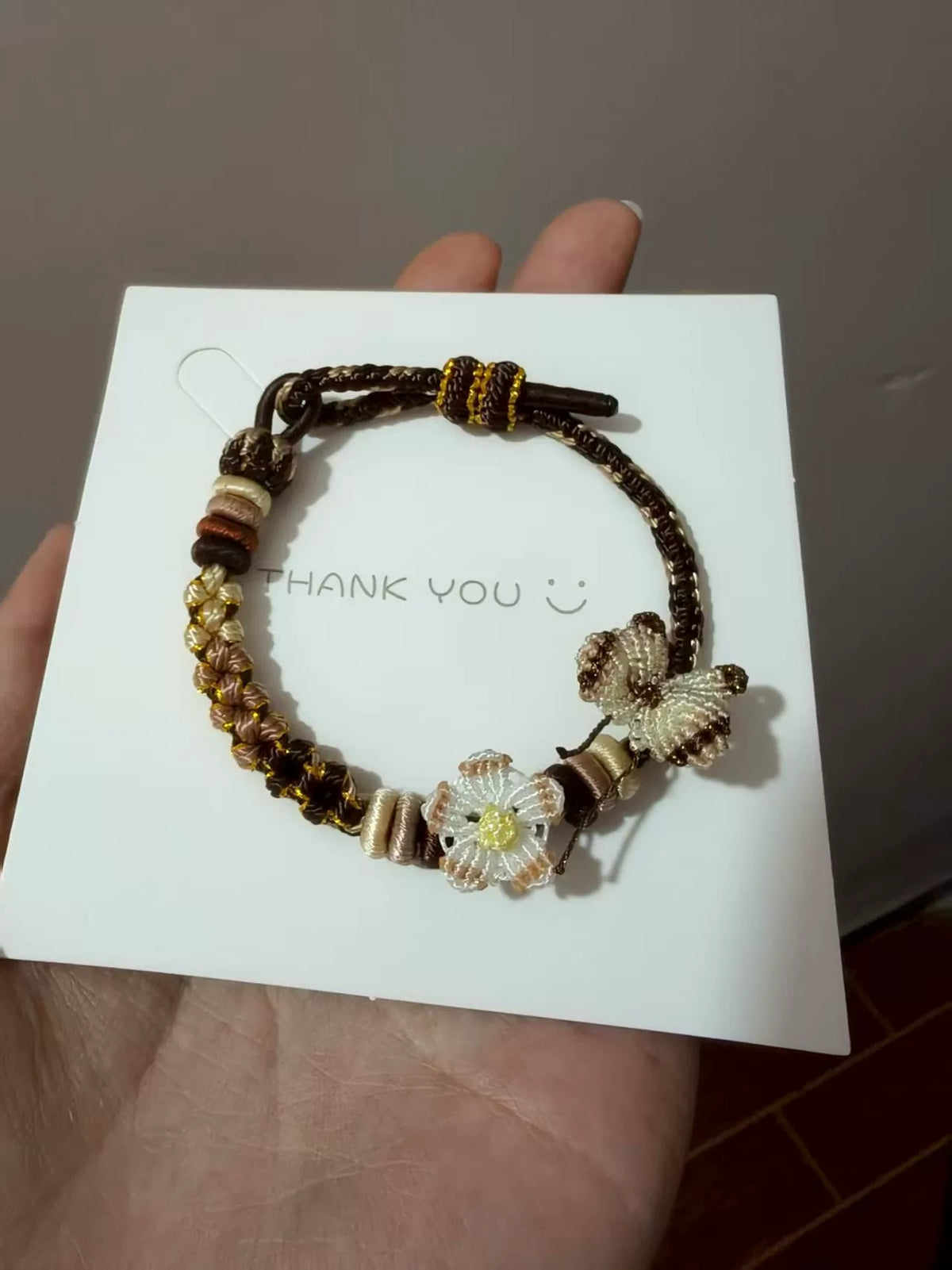 Handgjort flätat armband i brun snodd med blomberlock