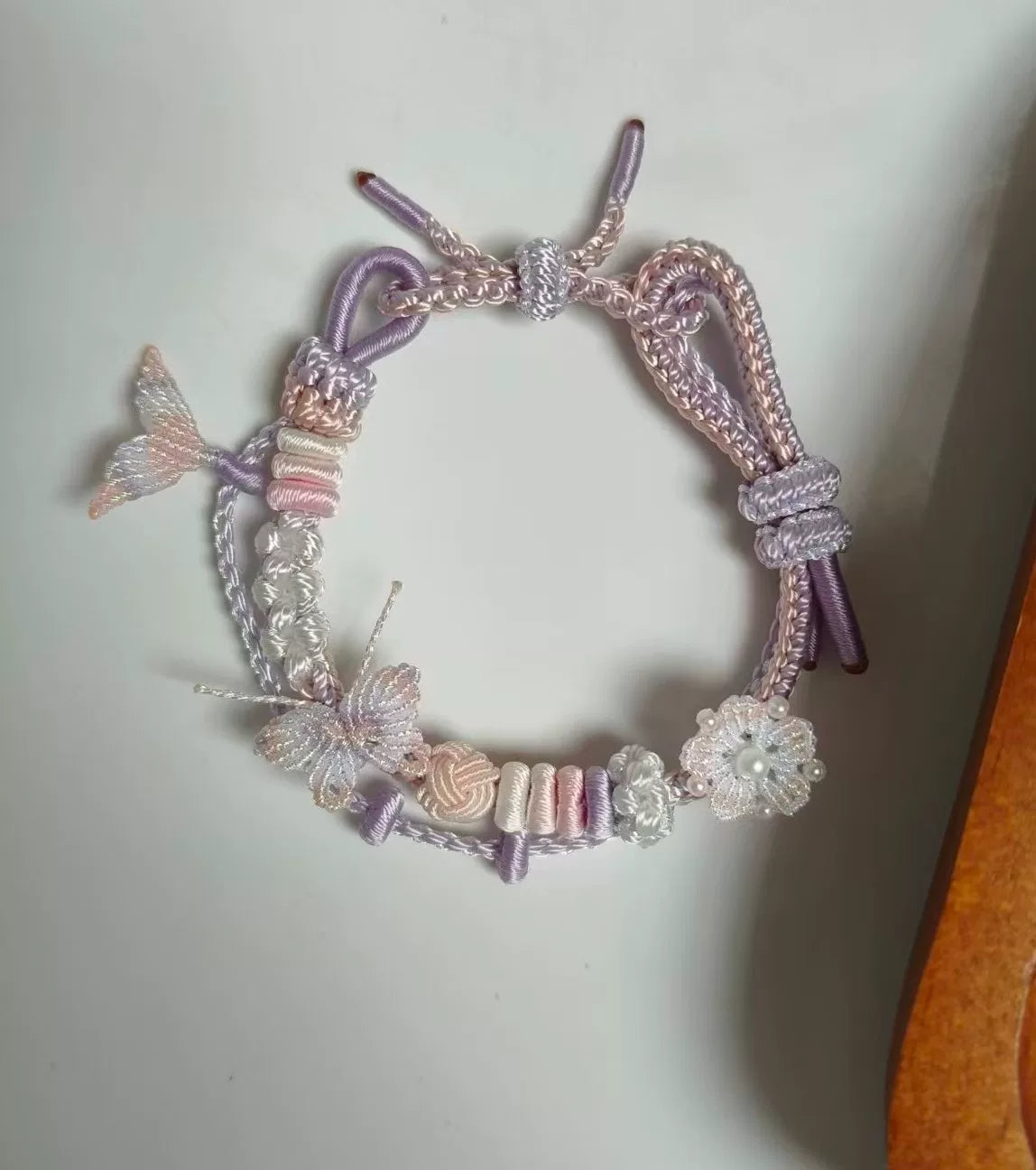 Pulseira tecida à mão com gradiente rosa e branco e charms de borboleta