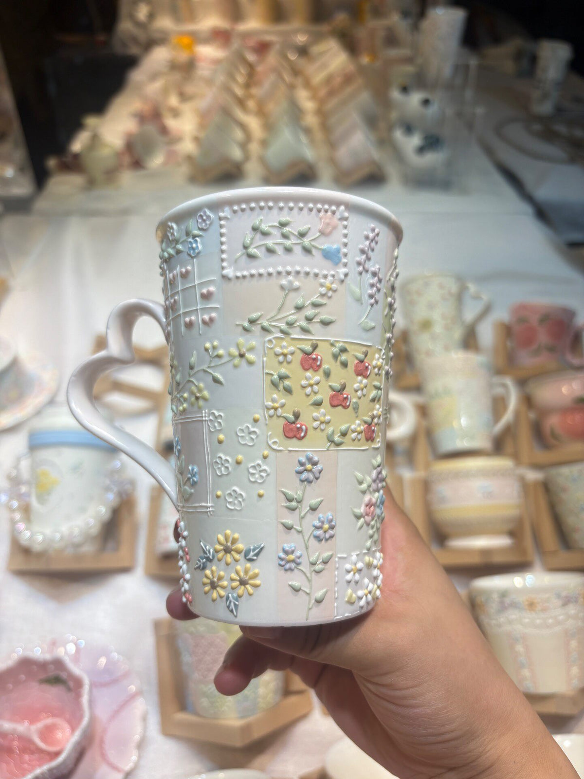 Keramiktasse mit pastellfarbenem Blumenrelief