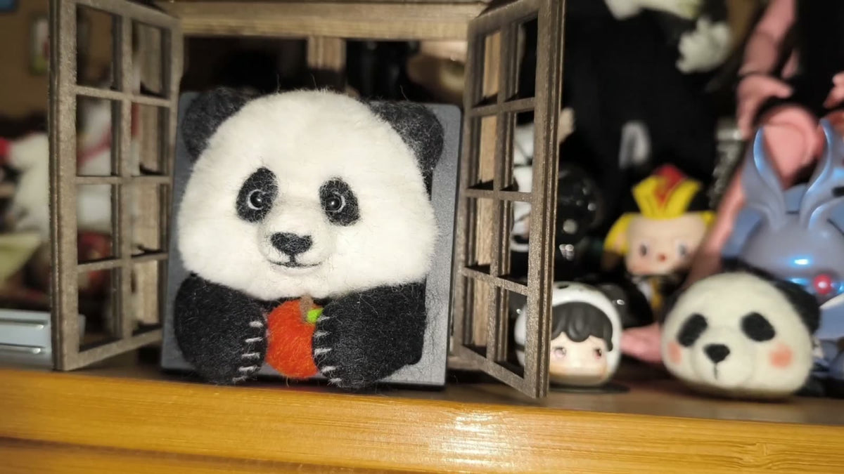 Handgjord ramdekor med panda i ullfilt som äter äpple