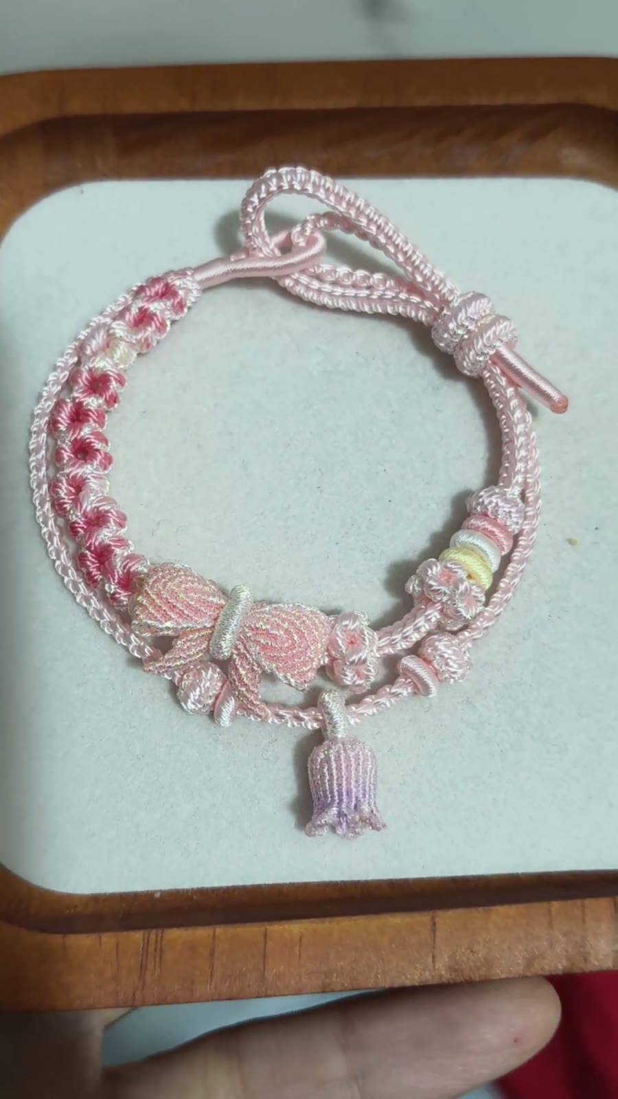 Bracciale in cordino intrecciato con sfumatura rosa e fiori