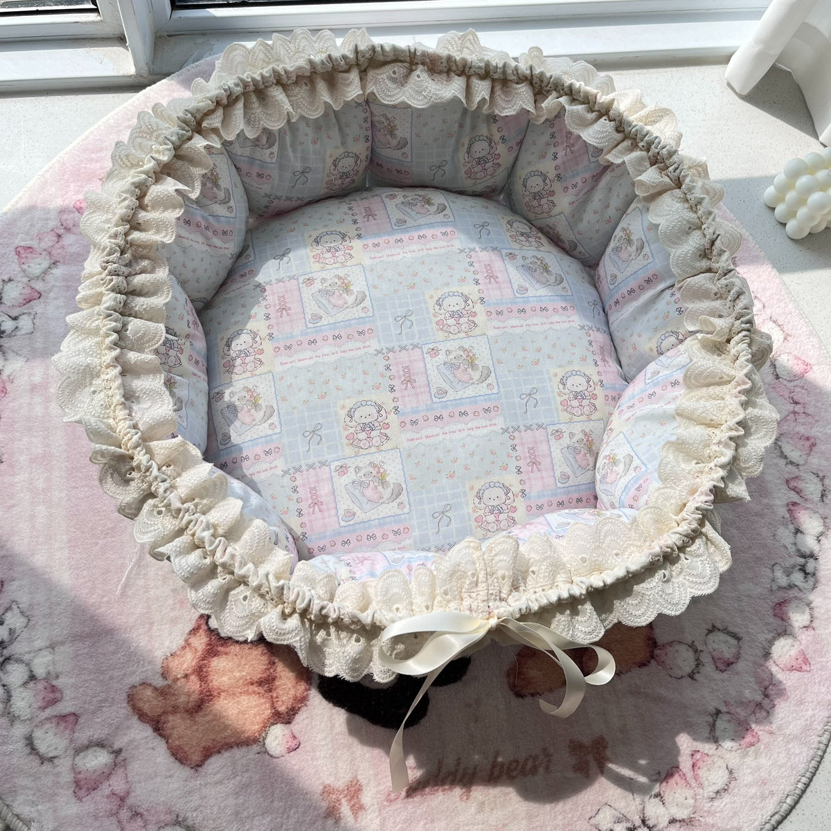 Blå husdjursbädd i lapptäcke med kattmotiv och gingham