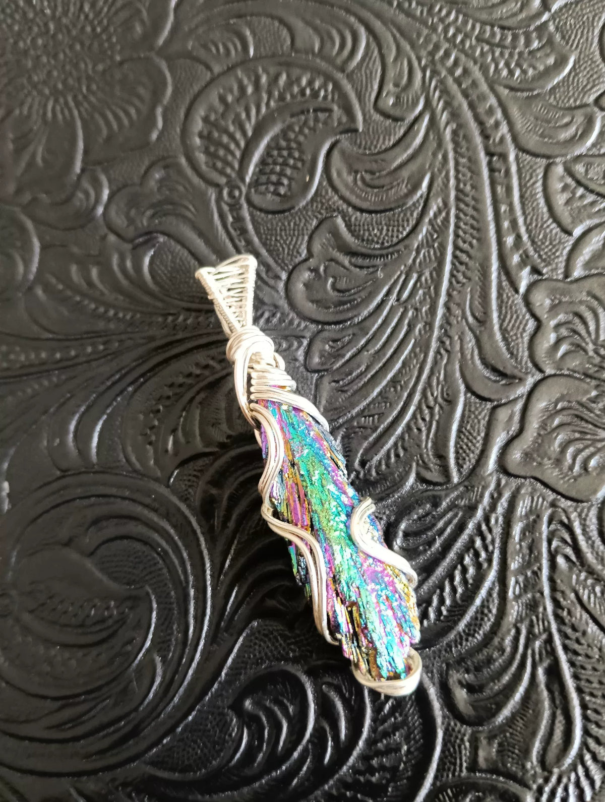 Pendente artesanal de mineral iridescente envolto em fio de cobre