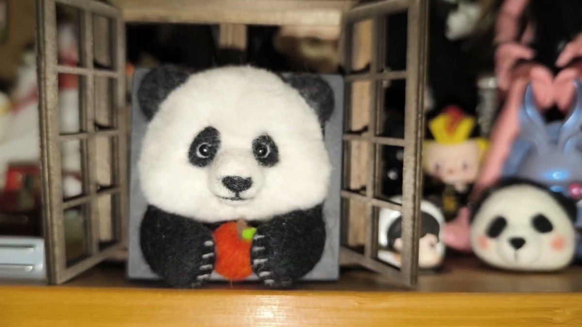 Handgjord ramdekor med panda i ullfilt som äter äpple