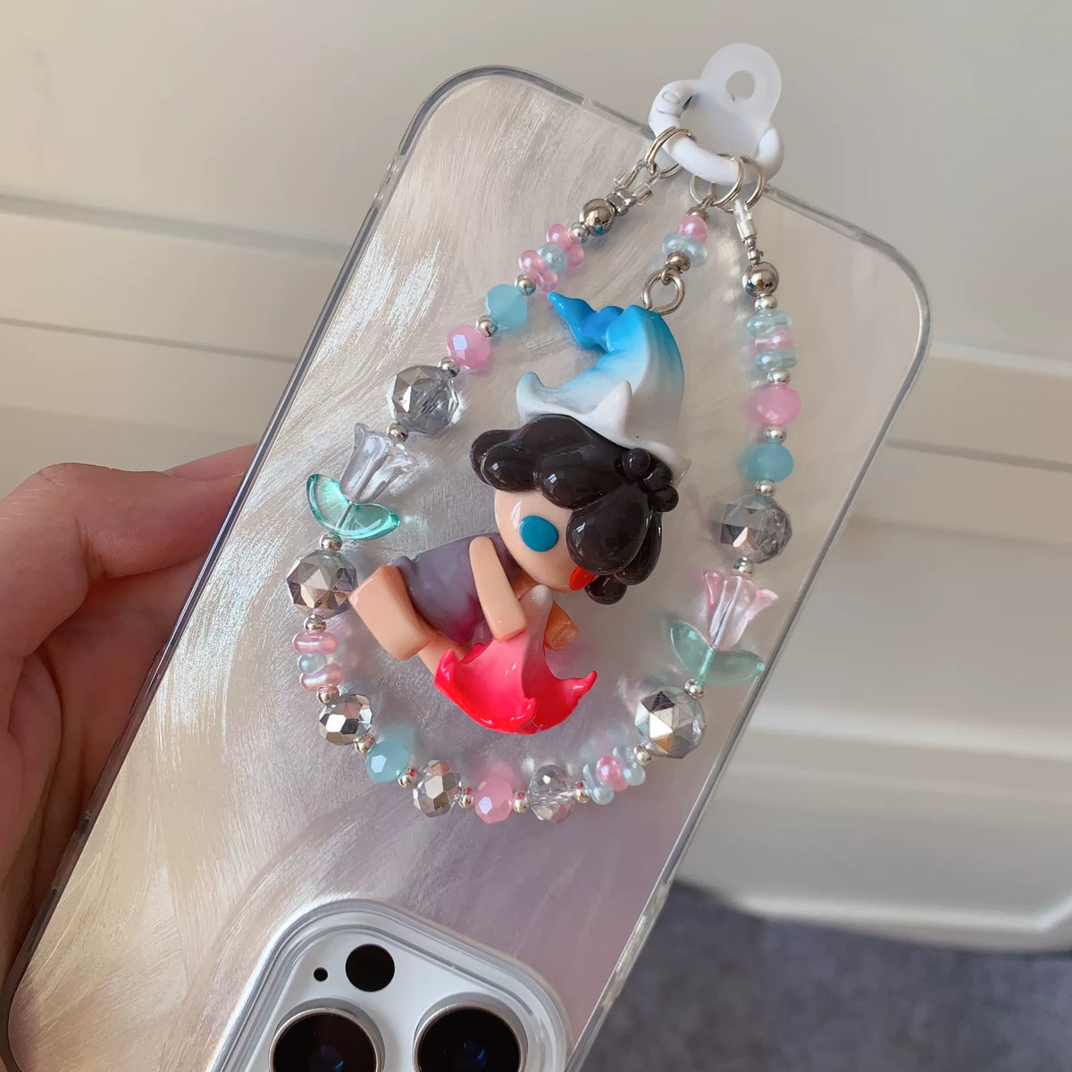 Handy-Anhänger mit Figur auf roter Blumenbasis