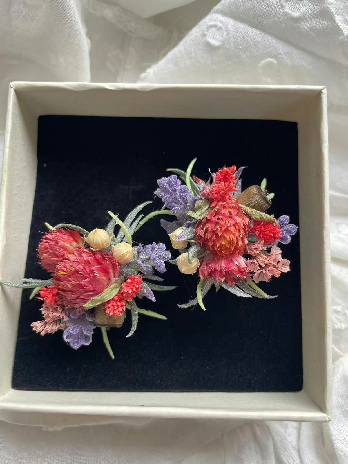 Coppia di anelli con fiori rossi conservati e scatola bianca