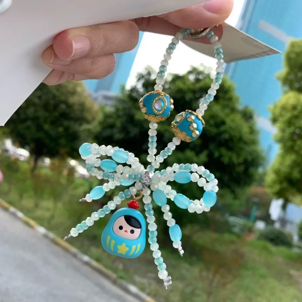 Hellblaue Daruma Handykette mit Perlen