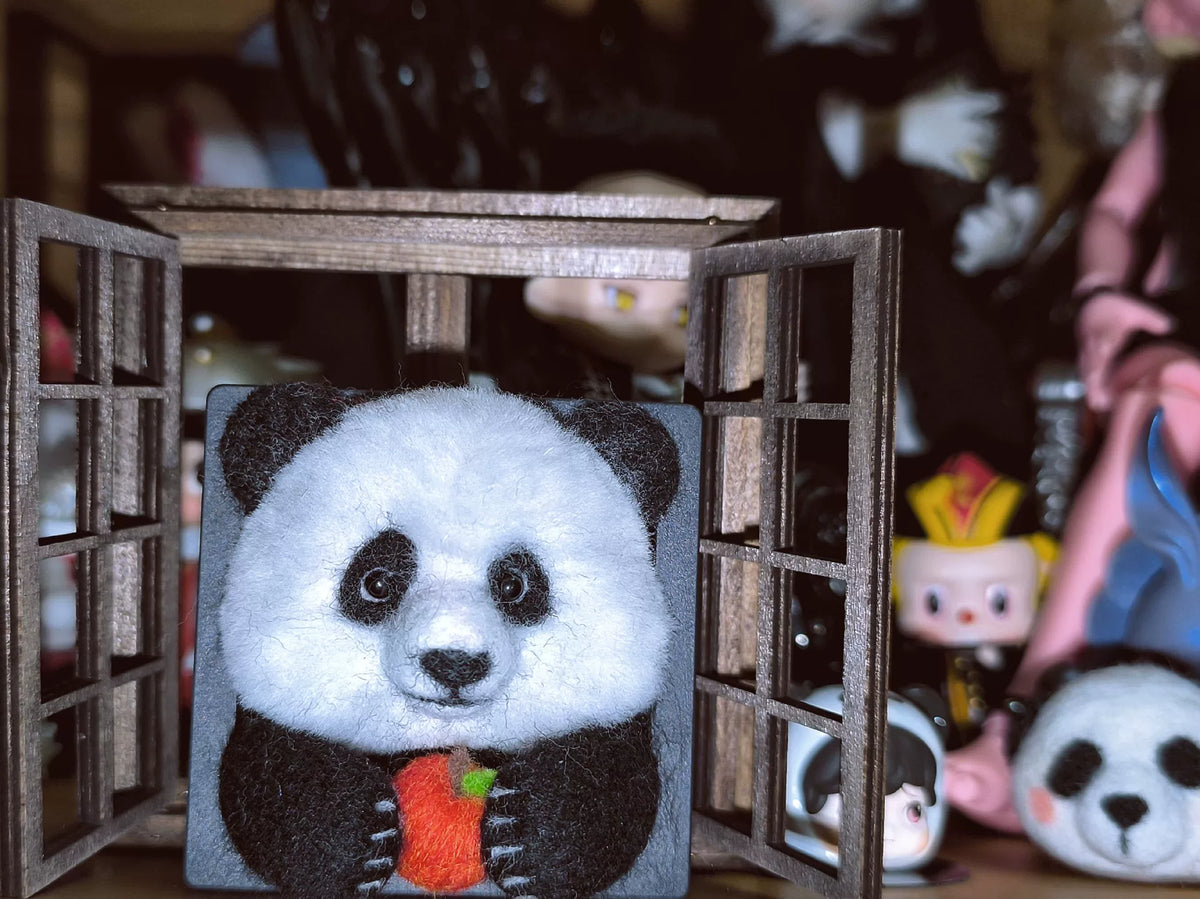 Handgjord ramdekor med panda i ullfilt som äter äpple