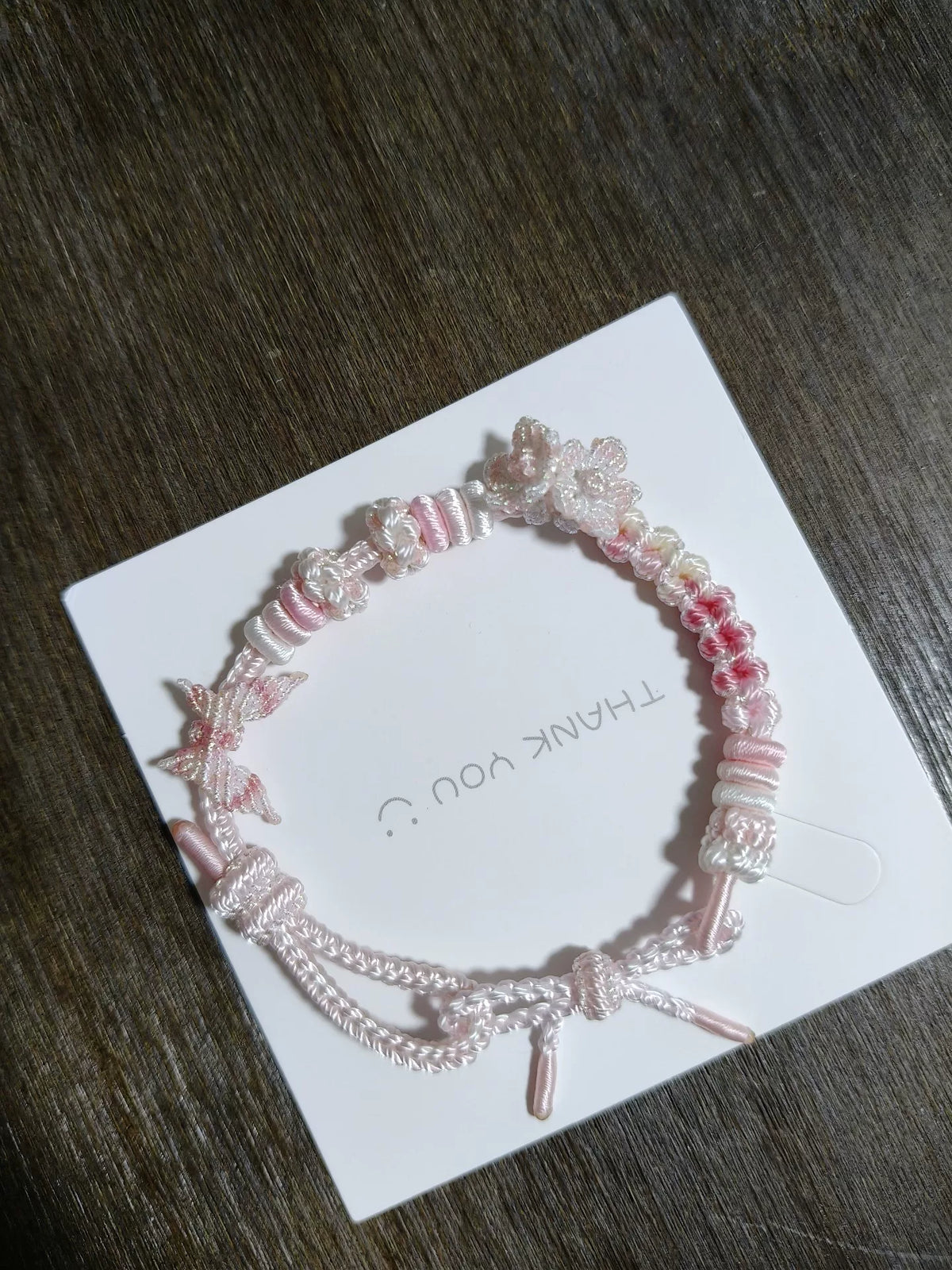 Pulsera tejida a mano en degradado rosa y blanco con detalles florales