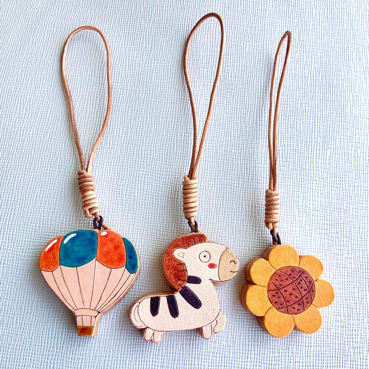Set de charms de cuero: globo aerostático, cebra y girasol