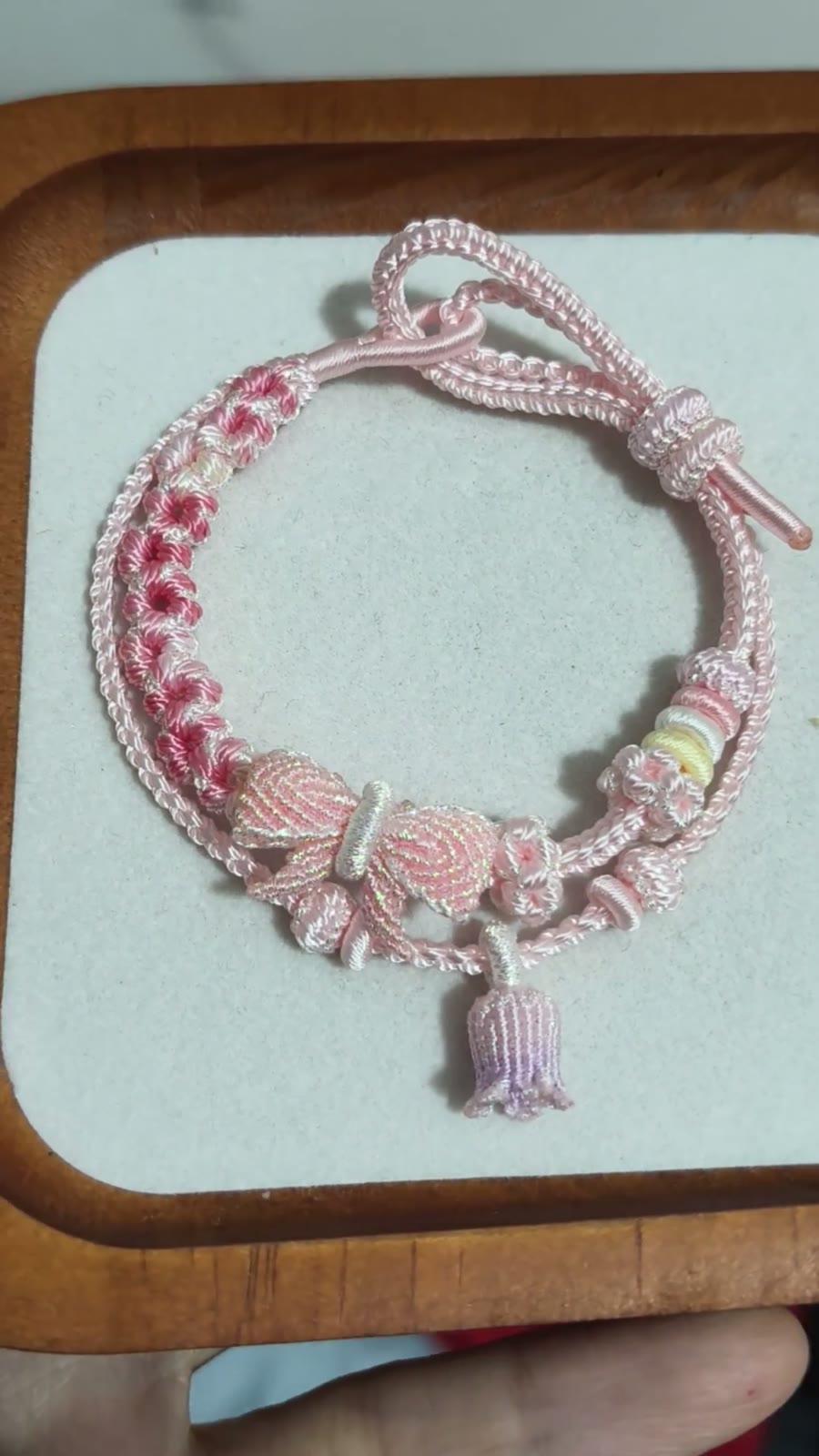 Bracciale in cordino intrecciato con sfumatura rosa e fiori