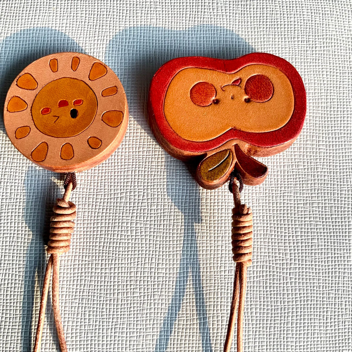 Handgesneden leren charms met zon en appel