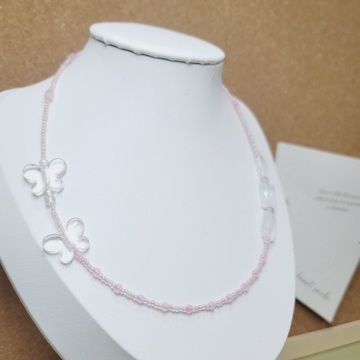 Collana artigianale in perline rosa e bianche con ciondoli a farfalla