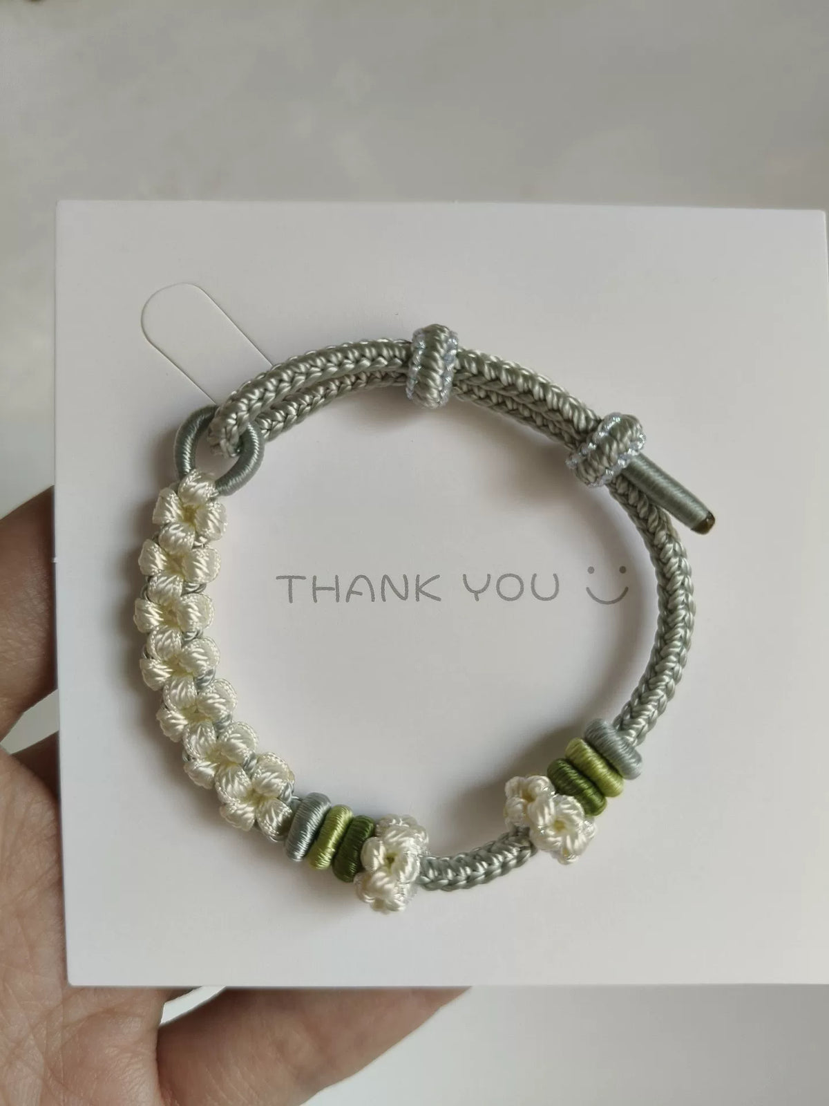 Pulsera de cordón trenzada a mano con flores verdes y blancas